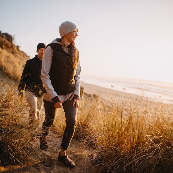 man and woman hiking along beach in chilly weather