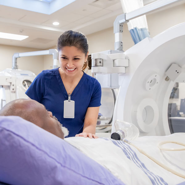 happy nurse assisting elderly patient into scanning machine